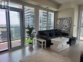 Toronto (Mimico) condo for rent - A living room with a couch, coffee table, and a large window overlooking a cityscape.