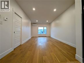 Dieppe apartment for rent - A spacious room with wooden flooring and white walls.