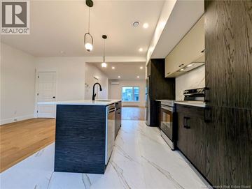 Dieppe apartment for rent - A modern kitchen with dark wood cabinets and a marble floor.