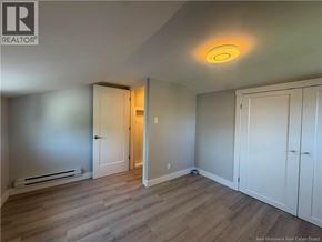 Moncton apartment for rent - A room with a wooden floor and white walls, with a door on the left and a cabinet on the right.