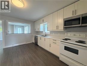 Moncton apartment for rent - A kitchen with white appliances and cabinets.