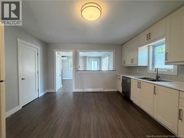 Moncton apartment for rent - A spacious kitchen with white cabinets and a wooden floor.