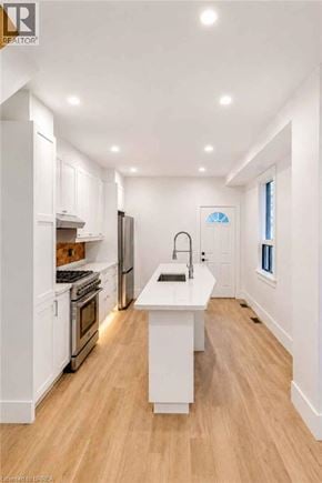 Hamilton apartment for rent - A modern kitchen with white cabinets and a wooden floor.