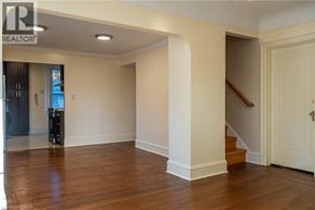 Hamilton apartment for rent - A spacious room with wooden floors and a staircase leading to another level.