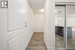 Waterdown condo for rent - A hallway with a white door and a glass door leading to a kitchen.