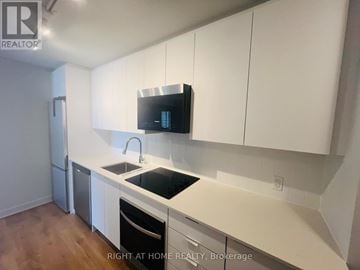 Vaughan (Concord) condo for rent - A kitchen with white cabinets and a black countertop.