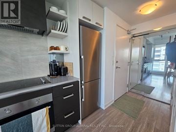 Toronto (High Park North) condo for rent - A kitchen with a stainless steel refrigerator and a stove top oven.