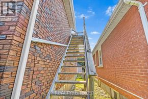 Kingston (Central City East) triplex for rent - A wooden staircase leads up to a balcony on a brick building.