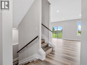 Leamington apartment for rent - A staircase with a black railing leads to a bright room with a large window.