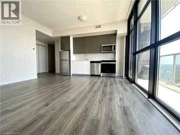 Kitchener condo for rent - A spacious kitchen with a refrigerator, oven, and microwave.