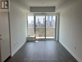 Toronto (Regent Park) condo for rent - A room with a view of the city skyline through a large window.
