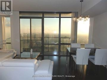Toronto (Bay Street Corridor) condo for rent - A living room with a view of the city at sunset.