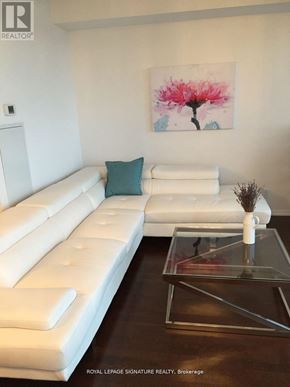 Toronto (Bay Street Corridor) condo for rent - A white leather sofa with a glass coffee table in front of it.