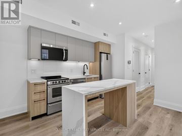 Toronto (Clanton Park) multi-family for rent - A modern kitchen with a white island in the middle.