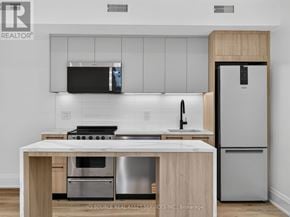 Toronto (Clanton Park) multi-family for rent - A modern kitchen with a stainless steel refrigerator and a wooden island.
