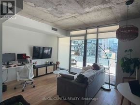 Toronto (Waterfront Communities) condo for rent - A living room with a couch, a chair, a television, and a window with a view of the city.