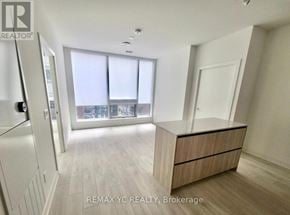 Toronto (Waterfront Communities) condo for rent - A spacious, well-lit room with a large window and a wooden cabinet.