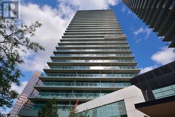 Toronto (Willowdale West) condo for rent - A tall building with many windows and balconies is seen from below.