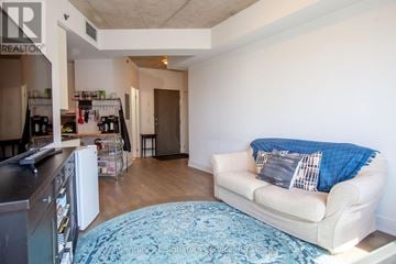 Toronto (Moss Park) condo for rent - A living room with a couch and a kitchen area in the background.