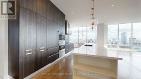 Toronto (Waterfront Communities) condo for rent - A modern kitchen with dark wood cabinets and a large window overlooking the city.
