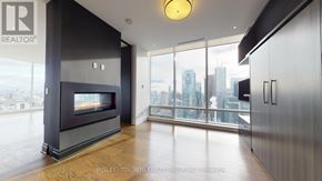 Toronto (Waterfront Communities) condo for rent - A modern living room with a fireplace and a view of the city.