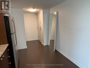 Toronto (Niagara) condo for rent - A hallway with a refrigerator on the left and a door on the right.