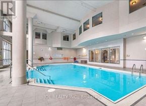 Toronto (Woburn) condo for rent - A large indoor swimming pool with a slide and a person sitting on the edge.