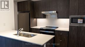 Richmond Hill (Jefferson) townhouse for rent - A modern kitchen with dark wood cabinets and stainless steel appliances.