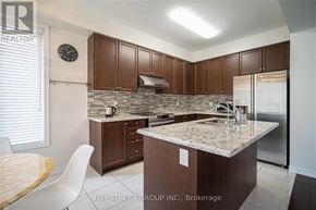 Markham (Berczy) townhouse for rent - A kitchen with a granite countertop and wooden cabinets.