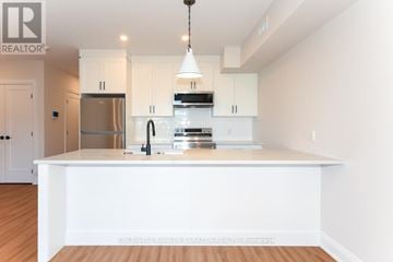 Ottawa apartment for rent - A modern kitchen with white cabinets and a wooden floor.