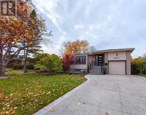 Mississauga (Clarkson) apartment for rent - A house with a driveway and a tree with orange leaves.