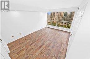 Mississauga (City Centre) condo for rent - A room with wooden flooring and a window overlooking a cityscape.