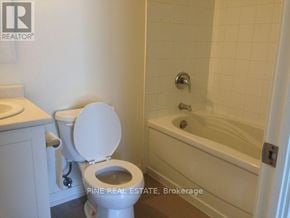 Toronto (Dovercourt-Wallace Emerson-Junction) condo for rent - A white toilet is next to a bathtub in a bathroom.