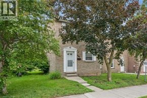 Waterloo townhouse for rent - A house with a white door and windows is surrounded by greenery.