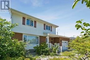 Fort Erie (Lakeshore) apartment for rent - A house with a white exterior and a red roof is surrounded by greenery.