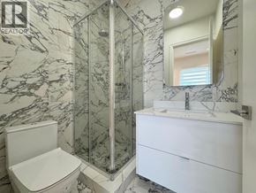 Richmond apartment for rent - A bathroom with a marble wall and a white toilet.