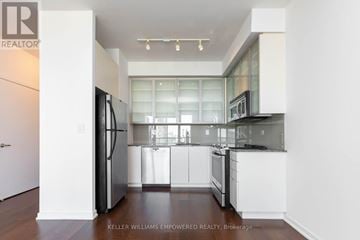 Toronto (Church-Yonge Corridor) condo for rent - A modern kitchen with white cabinets and a glass window.
