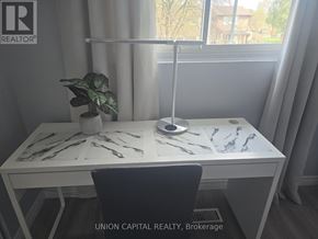 Toronto (Malvern) townhouse for rent - A desk with a plant and a lamp in a room with a window.