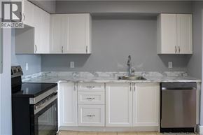 Moncton apartment for rent - A kitchen with white cabinets and a marble countertop.