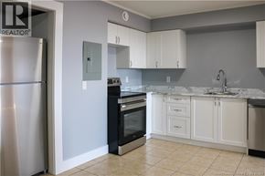 Moncton apartment for rent - A kitchen with white cabinets and a marble countertop.