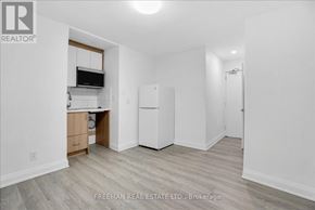 Toronto (South Parkdale) apartment for rent - A white kitchen with a refrigerator, cabinets, and a microwave.