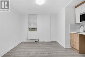 Toronto (South Parkdale) apartment for rent - A white room with a wooden floor and a small kitchenette.