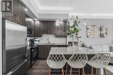 Toronto (Edenbridge-Humber Valley) condo for rent - A modern kitchen with a large island and stainless steel appliances.
