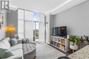 Toronto (Edenbridge-Humber Valley) condo for rent - A living room with a white couch, a grey ottoman, a television, and a window with a view of the city.