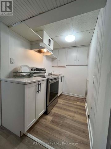 St. Catharines (Burleigh Hill) apartment for rent - A kitchen with white cabinets and a wooden floor.