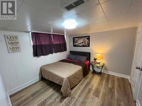 St. Catharines (Burleigh Hill) apartment for rent - A bedroom with a bed, a nightstand with a lamp, and a framed picture on the wall.