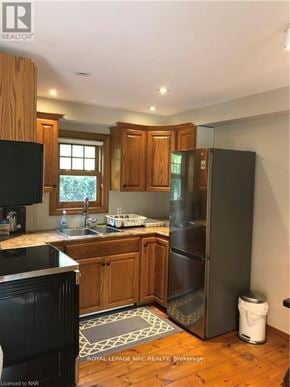 Niagara-On-The-Lake (Town) apartment for rent - A kitchen with wooden cabinets and a black fridge.
