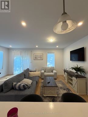 Barrie (East Bayfield) townhouse for rent - A living room with a grey couch and a white chair.