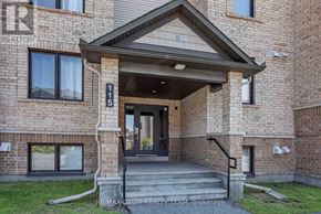 Ottawa condo for rent - The front entrance of a building with a glass door and steps leading up to it.