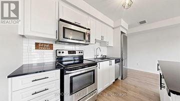 Toronto (Downsview-Roding-Cfb) townhouse for rent - A kitchen with white cabinets and black countertops.